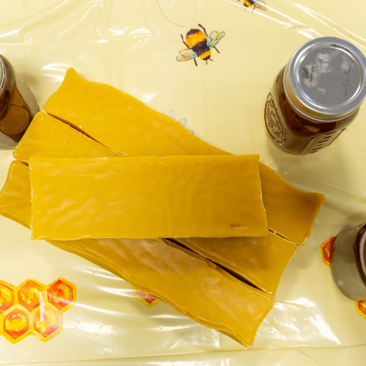 Slabs of beeswax laid out from above, jars of honey at the edges of the frame