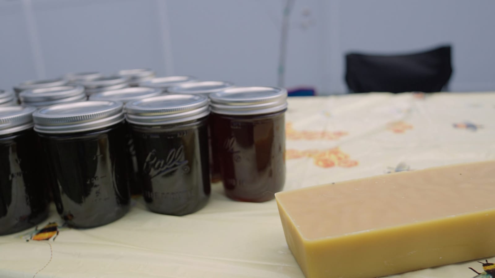 Quart jars of dark honey on our market table, with a slab of beeswax beside them